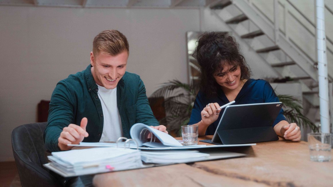 Comment vivre sans dettes ? Un jeune couple travaille ensemble sur le carnet de gestion financière du foyer
