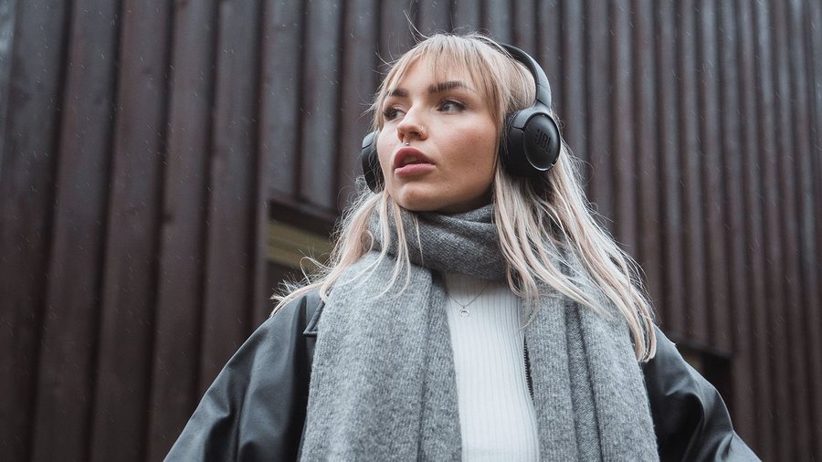 Construire sa fortune avec peu d’argent : comment faire ? Une jeune femme avec un casque audio regarde au loin