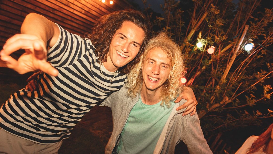 Deux jeunes hommes sourient face à la caméra