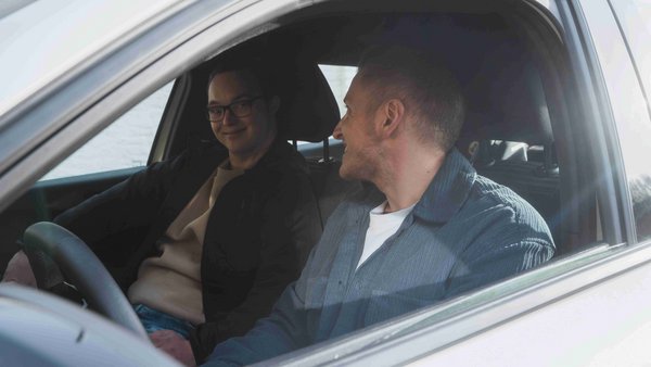 Est-ce que l’achat d’une voiture a du sens ? Deux jeunes hommes assis dans une voiture se sourient