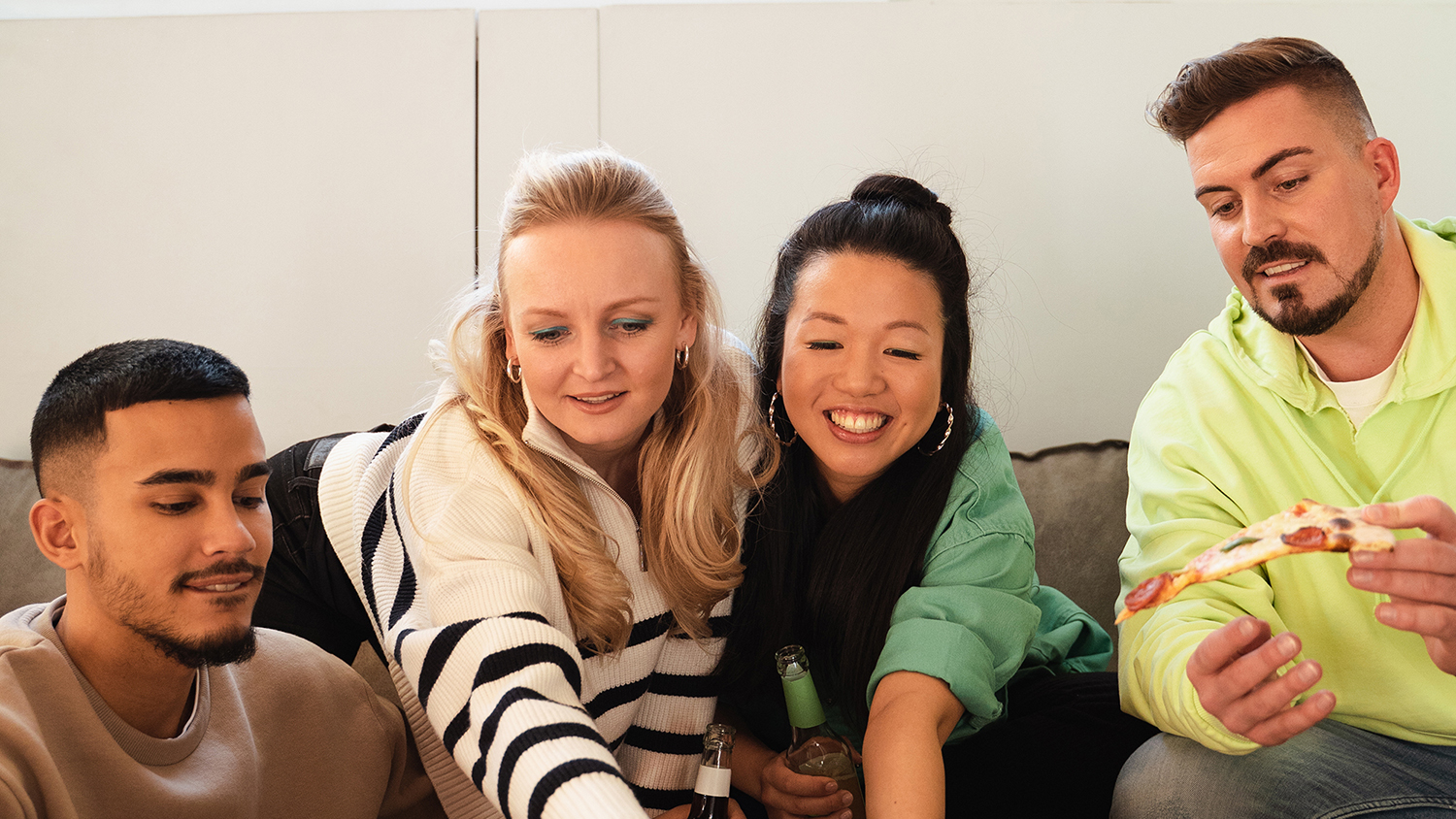 Comment fonctionne la colocation ? Quatre jeunes adultes rigolent assis sur un canapé